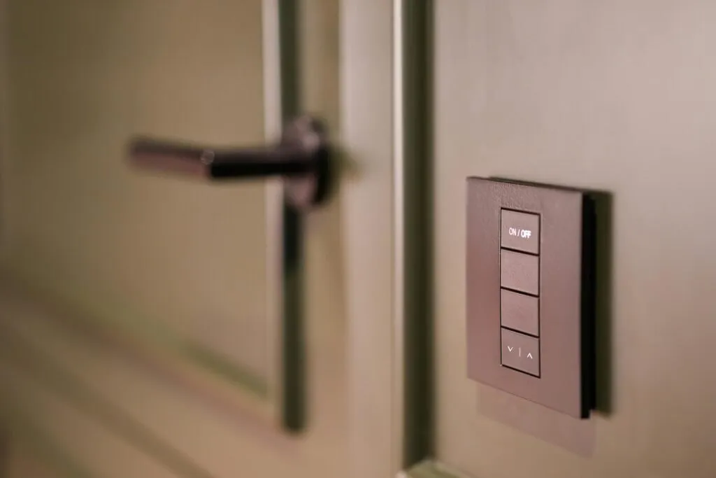 A smart light switch on a wall next to a modern door handle, emphasizing home automation.