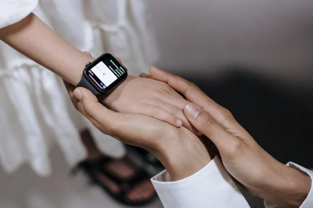 A close-up of an adult holding a child's hand wearing a smartwatch, showcasing technology and care.
