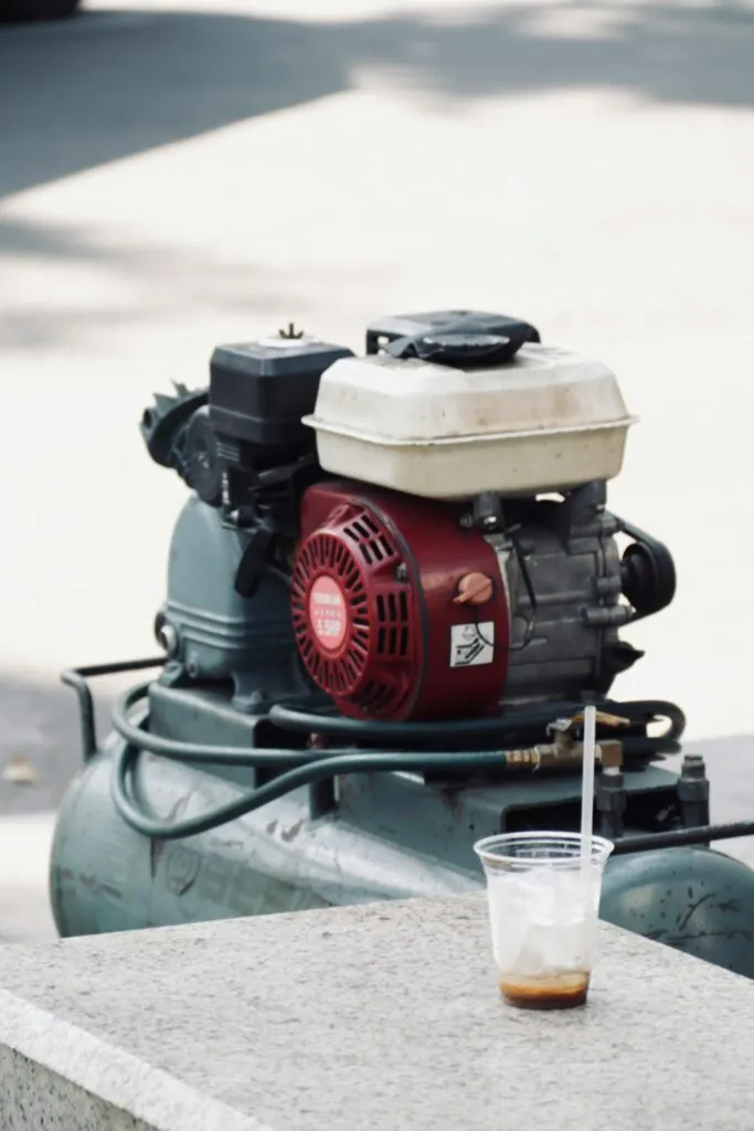 A close-up view of an industrial air compressor with a plastic cup in sunlight.