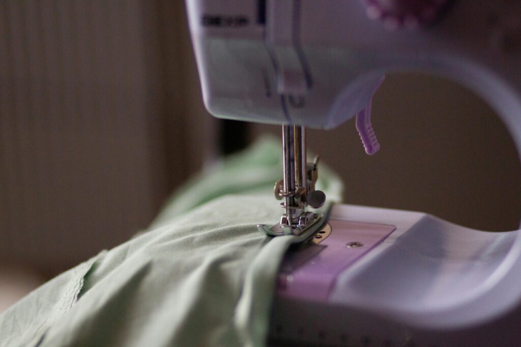 Detailed view of a sewing machine needle stitching green fabric.