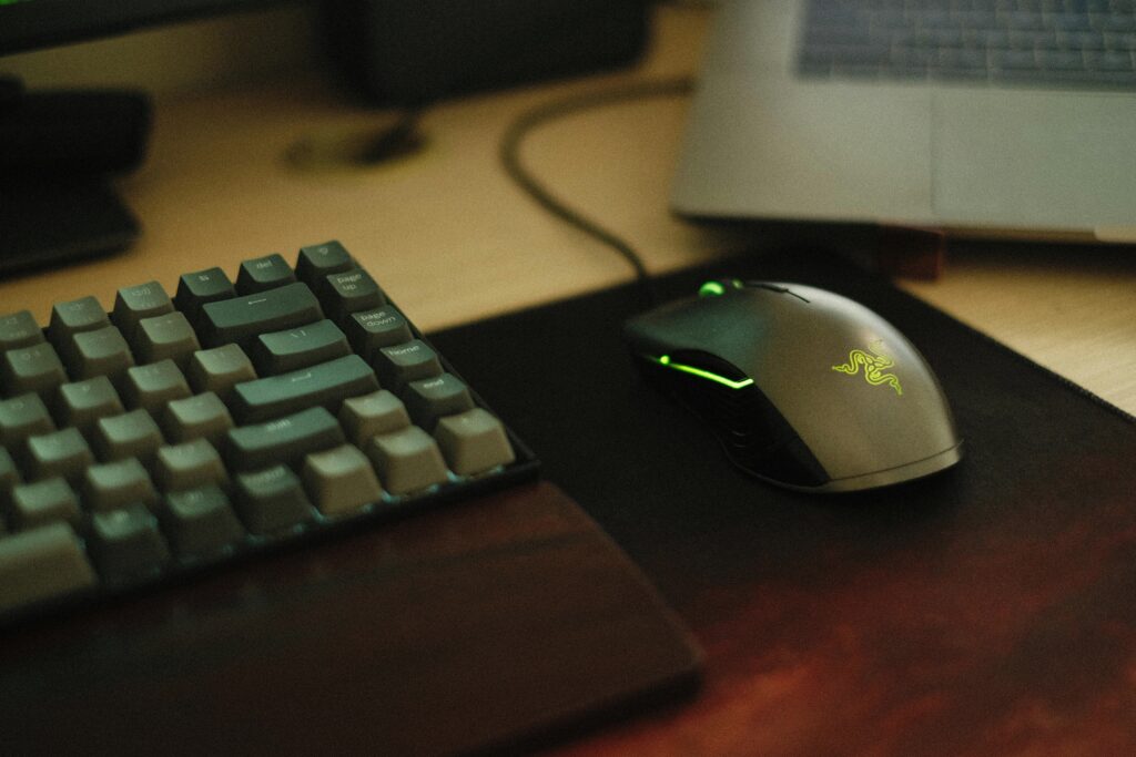 Close-up of a gaming mouse with illumination next to a mechanical keyboard on a desk.