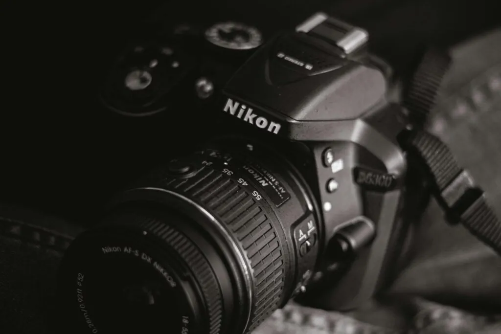 Artistic close-up of a DSLR camera in a black and white setting, emphasizing details and texture.