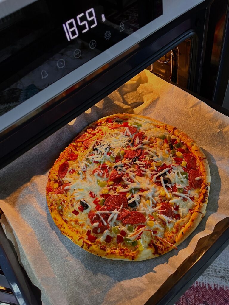 Cheesy pepperoni pizza fresh out of the oven, topped with assorted vegetables.